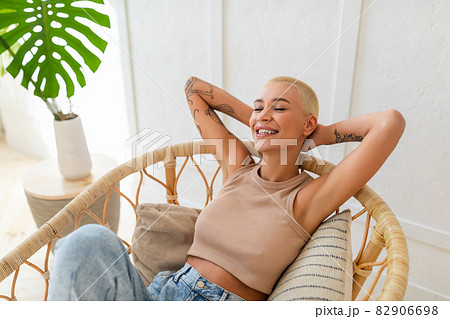 Weekend recreation. Young lady sitting in cozy modern chair with eyes closed, resting and relaxing at home Weekend recreation. Young lady sitting in cozy modern chair with eyes closed, resting and relaxing at home 82906698