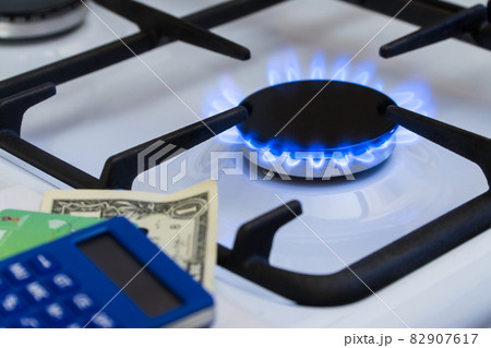 Shortage and gas crisis. Money and a calculator on the background of a burning gas stove Shortage and gas crisis. Money and a calculator on the background of a burning gas stove 82907617