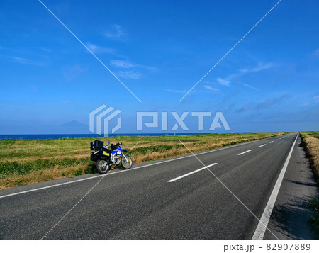 青空と地平線へ延々と遠くに続く道とバイク 82907889