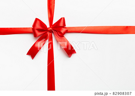 Top view of Red ribbon rolled and red bow isolated on colored background. Flat lay with copy space Top view of Red ribbon rolled and red bow isolated on colored background. Flat lay with copy space 82908307
