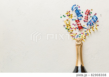 Creative flat lay composition with bottle of champagne and space for text on color background. Champagne bottle with colorful party streamers. holiday or christmas concept Creative flat lay composition with bottle of champagne and space for text on color background. Champagne bottle with colorful party streamers. holiday or christmas concept 82908308