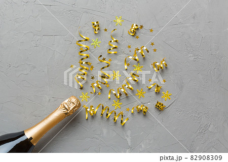 Creative flat lay composition with bottle of champagne and space for text on color background. Champagne bottle with colorful party streamers. holiday or christmas concept Creative flat lay composition with bottle of champagne and space for text on color background. Champagne bottle with colorful party streamers. holiday or christmas concept 82908309