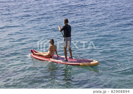 Young couple on stand up paddleboard surfboard surfing together 82908894