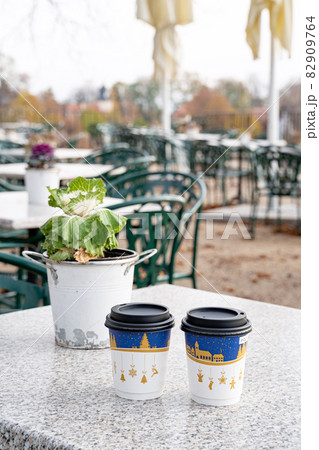 Houseplant in bucket and two recyclable paper coffee cups with christmas print Houseplant in bucket and two recyclable paper coffee cups with christmas print 82909764