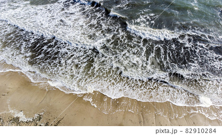 Aerial drone view flight over sea waves that roll onto sandy shore. Aerial drone view flight over sea waves that roll onto sandy shore. 82910284