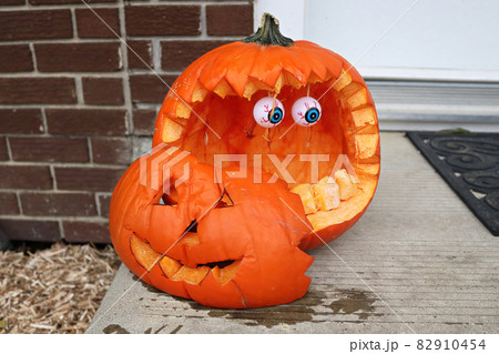 A carved pumkins sitting on a doorstep 82910454