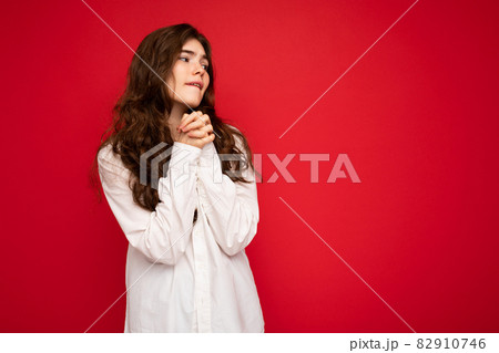 Portrait of beautiful young curly brunette woman wearing white shirt isolated on red background with Portrait of beautiful young curly brunette woman wearing white shirt isolated on red background with 82910746
