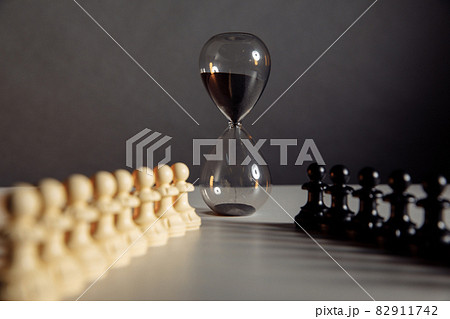 Hourglass and chess pieces. Sports and leisure concept. Hourglass and chess pieces. Sports and leisure concept. 82911742