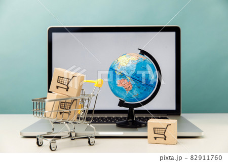 Online shopping and ecommerce concept. Globe and supermarket shopping cart with boxes near laptop Online shopping and ecommerce concept. Globe and supermarket shopping cart with boxes near laptop 82911760