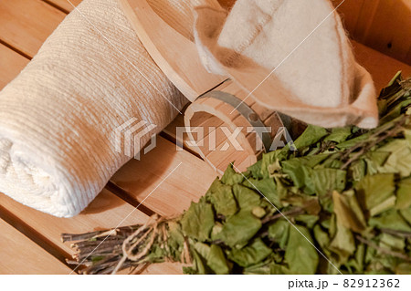 Traditional old Russian bathhouse SPA Concept. Interior details Finnish sauna steam room with traditional sauna accessories set towel birch broom scoop felt. Relax country village bath concept. 82912362