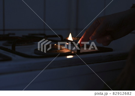 Woman trying to turn on gas with a match flame. Female hand trying to turn on old gas stove. No gas, Winter and cold period concepts. Lack of gas in the pipeline Woman trying to turn on gas with a match flame. Female hand trying to turn on old gas stove. No gas, Winter and cold period concepts. Lack of gas in the pipeline 82912682