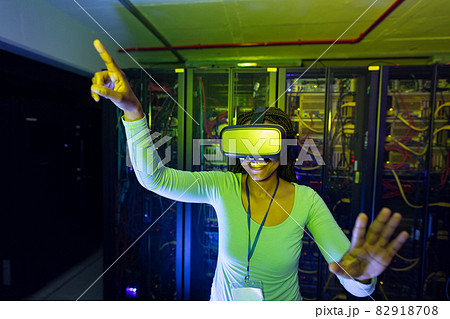 Happy african american female computer technician wearing vr headset and working in server room Happy african american female computer technician wearing vr headset and working in server room 82918708