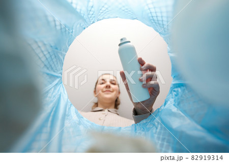 woman throwing hair spray bottle into trash can 82919314