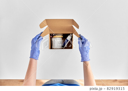 hands in gloves packing parcel box with cosmetics 82919315