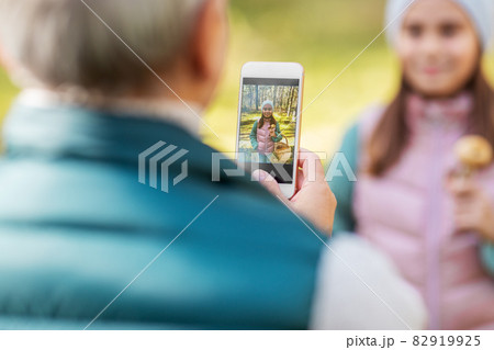 grandma photographing granddaughter with mushrooms grandma photographing granddaughter with mushrooms 82919925