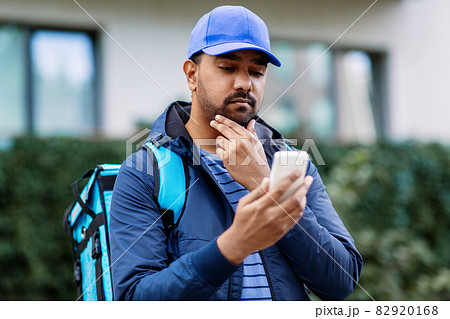 indian delivery man with bag and phone 82920168