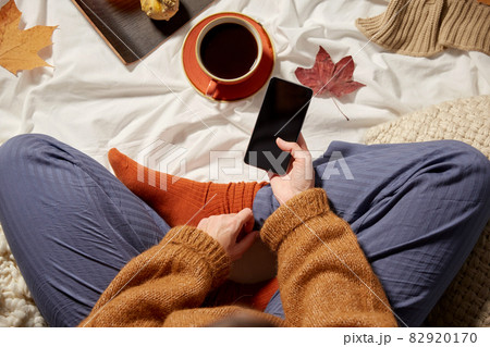 woman with smartphone at home in autumn 82920170