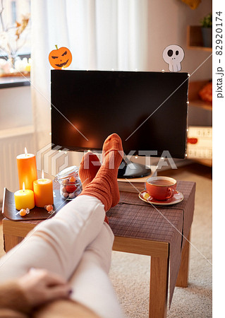 young woman watching tv at home on halloween 82920174