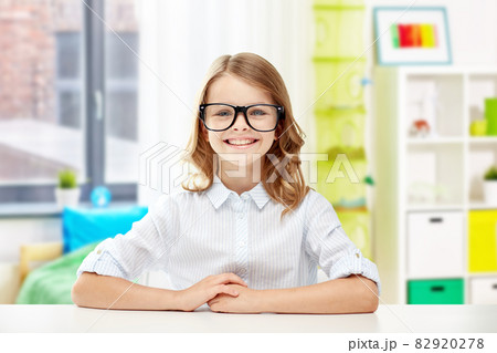 smiling student girl in glasses sitting at table smiling student girl in glasses sitting at table 82920278