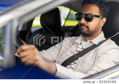 smiling indian man in sunglasses driving car 82920589