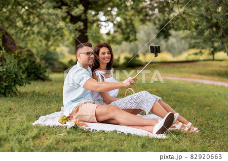 happy couple taking selfie at picnic in park 82920663