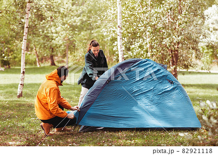 happy couple setting up tent outdoors happy couple setting up tent outdoors 82921118