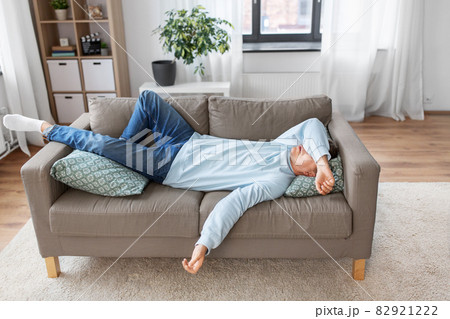 bored or lazy young man lying on sofa at home bored or lazy young man lying on sofa at home 82921222