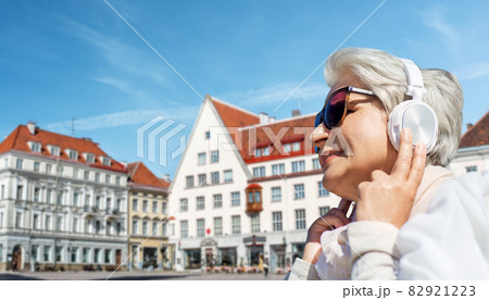 old woman in headphones listens to music outdoors old woman in headphones listens to music outdoors 82921223