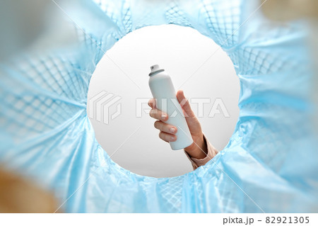 hand throwing hair spray bottle into trash can 82921305