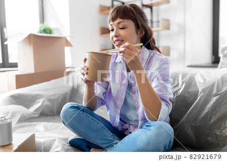 happy woman moving to new home and eating wok 82921679