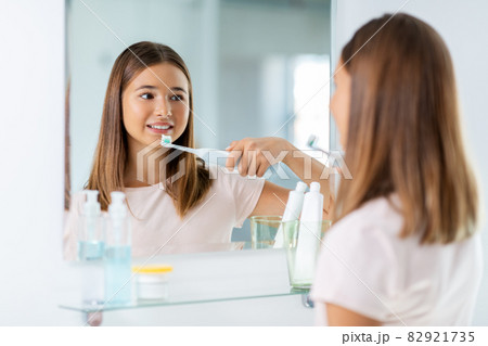 teen girl with electric toothbrush brushing teeth 82921735