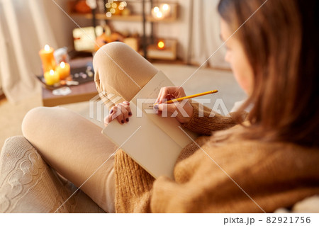 woman writing to diary at home on halloween 82921756