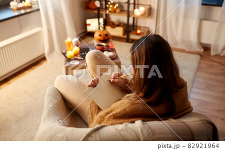 woman writing to diary at home on halloween 82921964