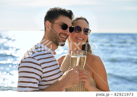 happy couple drinking champagne on summer beach happy couple drinking champagne on summer beach 82921973