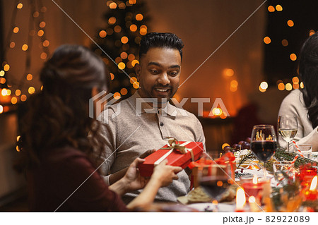 happy friends giving christmas presents at home 82922089