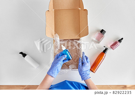hands in gloves packing parcel box with cosmetics 82922235
