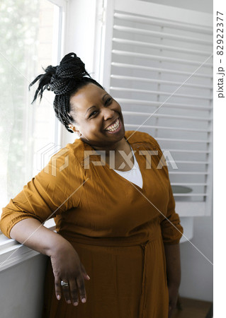 Portrait of smiling woman standing at window Portrait of smiling woman standing at window 82922377