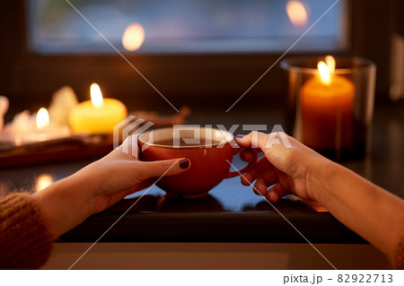 hands with cup of tea on window sill in autumn 82922713
