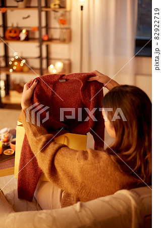 woman taking cardigan from shopping bag at home 82922719