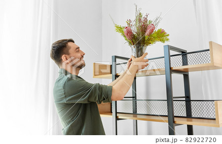 man decorating home with flowers in vase 82922720