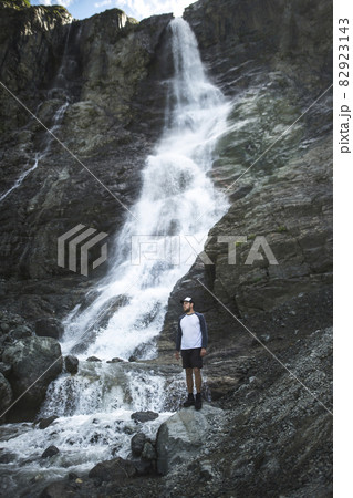 Russia, Karachay-Cherkessia, Arkhyz, Man standing near Sofiyskiye Vodopady waterfall in Caucasus Mountains Russia, Karachay-Cherkessia, Arkhyz, Man standing near Sofiyskiye Vodopady waterfall in Caucasus Mountains 82923143