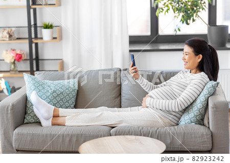 happy pregnant woman with smartphone at home 82923242