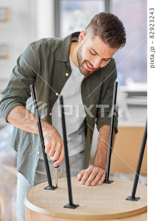 happy man assembling coffee table at new home 82923243
