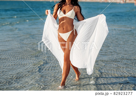 woman in bikini swimsuit with cover-up on beach woman in bikini swimsuit with cover-up on beach 82923277