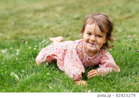happy little baby girl lying on grass in summer happy little baby girl lying on grass in summer 82923279