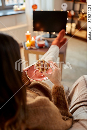 woman watching tv and eating waffle on halloween 82924121