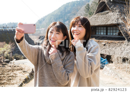 冬の西湖根場をバックに記念撮影する二人の女性 82924123