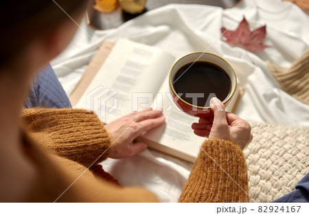 woman drinking coffee and reading book in autumn woman drinking coffee and reading book in autumn 82924167