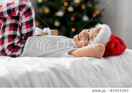 happy girl with christmas gift on bed at home 82924263