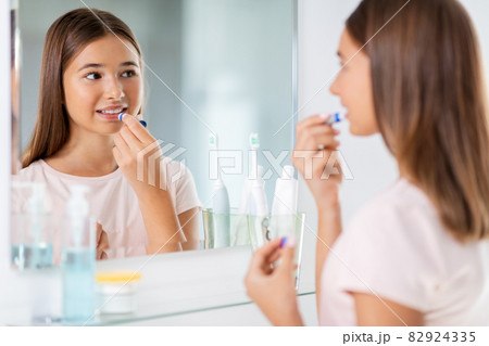 teenage girl applying lip balm at bathroom teenage girl applying lip balm at bathroom 82924335